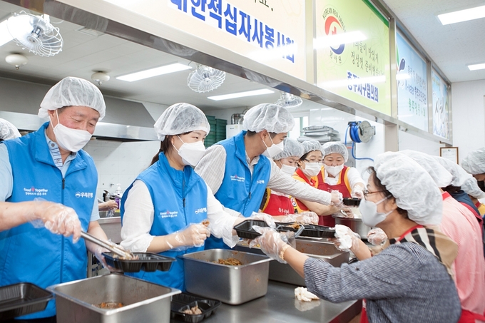 우리금융그룹 임직원 자원봉사단이 충북 충주시 충주봉사관(충주시 용산로 3)에서 대한적십자사와 함께 전달할 음식을 직접 만들고 도시락을 포장하는 봉사활동을 펼치고 있다. 사진/우리금융