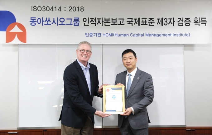 정재훈 동아쏘시오홀딩스 대표(오른쪽)와 제프 히긴스 HCMI 대표가 동아쏘시오그룹 인적자본보고 국제표준 제3자 검증 획득 기념 촬영을 하고 있다. @ 동아쏘시오홀딩스