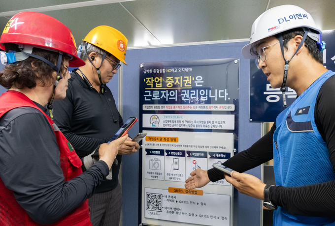 DL이앤씨 현장 안전관리자(우측 첫번째)가 현장 근로자들에게 안전신문고 접속 및 작업중지권 사용법에 대해 설명하고 있다. @ DL이앤씨